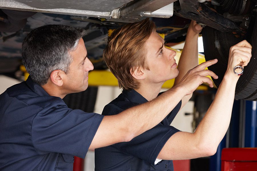 Specialized Business Insurance - A Senior Mechanic is Mentoring a Junior Mechanic While Fixing a Car at an Auto Shop